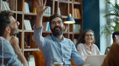 Ambitious male employee raise hand ask question to female presenter at meeting, man show activity at teambuilding with multiethnic colleagues, diverse workers brainstorm at office education briefing