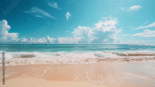 experience the warmth of summer through the ocean as white clouds drift across a blue sky, with gentle waves lapping at the shore