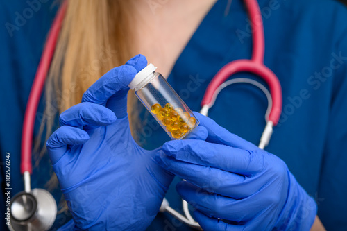 Lekarz trzyma w dłoniach fiolkę wypełnioną kapsułkami z lekarstwem placebo