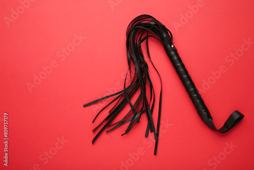 Leather bdsm whip on red background. Erotic toys for BDSM