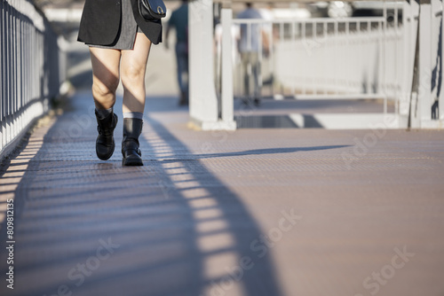 Woman's legs in seven-league boots taking a walk on a metal surface of an elevated walkway
