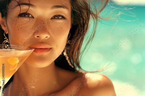 A close-up of an Asian woman with bronzed skin, slim yet curvaceous, sipping a cocktail in a bikini