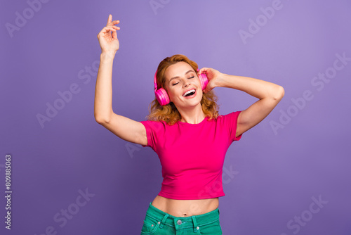Photo of lovely cheerful glad woman wear trendy pink clothes enjoy music isolated on purple color background