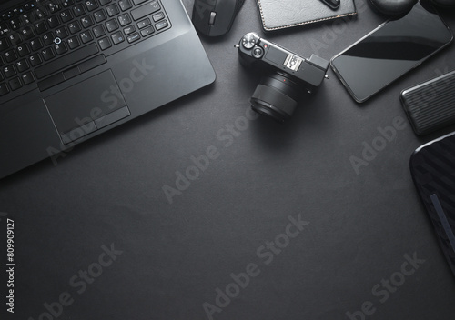 Modern black gadgets and accessories. Laptop, camera, smartphone, stere, external hard drive, USB flash drive, power bank on a black background. Photographer's equipment. Working space.