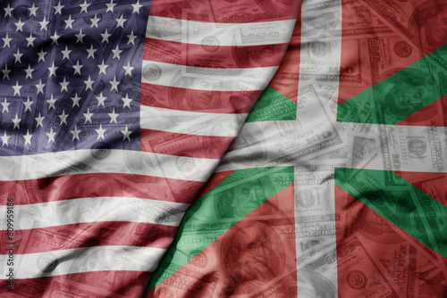 big waving colorful flag of united states of america and national flag of basque country on the dollar money background. finance concept.