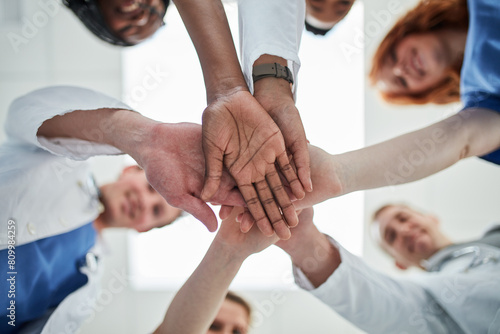 People, hands together and below with medical team for meeting, unity or motivation at hospital. Low angle or closeup of group piling or touching in collaboration, solidarity or mission at clinic