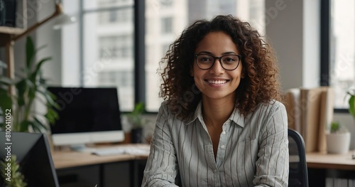  Modern day worker, Portrait of happy biracial business woman freelancer sit by computer at comfy workplace at corporate workspace or at home, Smiling young indian lady office employee look at camera