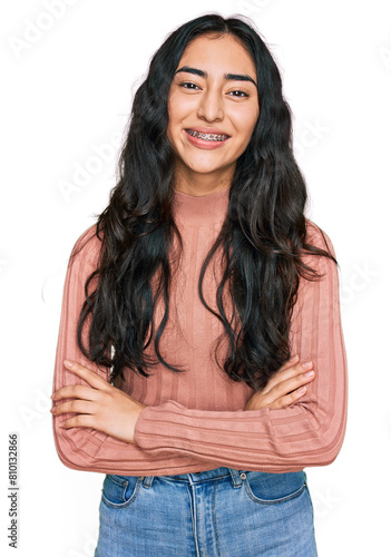 Hispanic teenager girl with dental braces wearing casual clothes happy face smiling with crossed arms looking at the camera. positive person.