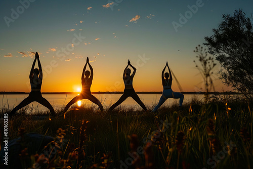 Four people doing yoga in the sunset.