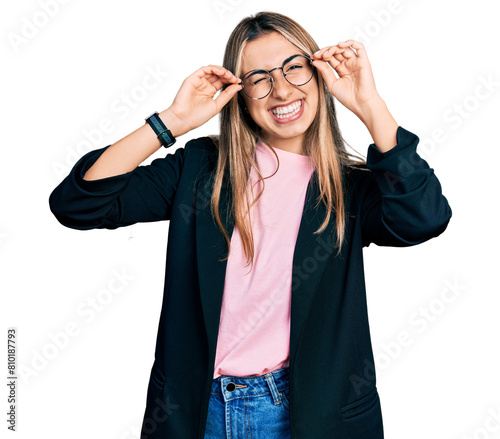 Hispanic young woman wearing elegant jacket and glasses winking looking at the camera with sexy expression, cheerful and happy face.