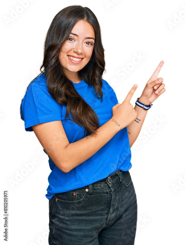 Beautiful brunette young woman wearing casual clothes smiling and looking at the camera pointing with two hands and fingers to the side.