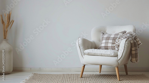 Modern white armchair with plaid near light wall