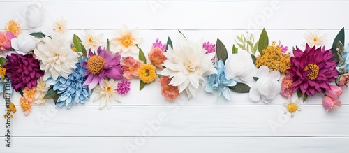 A white wooden background features a captivating arrangement of flowers viewed from above with ample copy space available