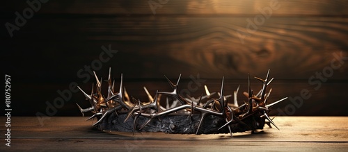 A Christian crown of thorns containing metal nails is placed on a wooden desk with copy space image