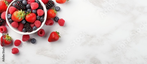 A bowl filled with cereals and red berries is seen from a top perspective placed on a white marble table The image is horizontal and includes copy space