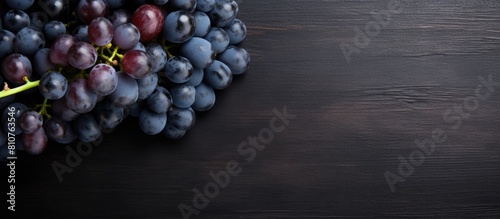 The top view shows a collection of plump ripe blue grapes resting on a dark scratched surface in this copy space image