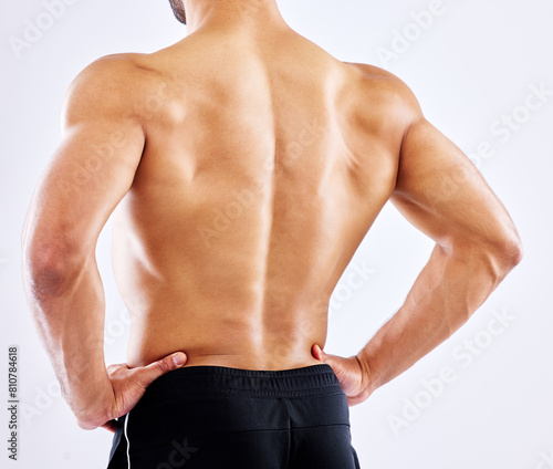 Man, back and fitness with muscular body from workout, exercise or training on a white studio background. Rear view of male person or shirtless bodybuilder with strong trapezius muscles from strength