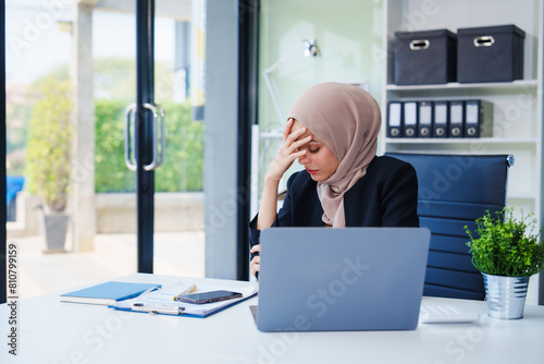 Diligent Muslim businesswoman, donning a hijab, diligently works at her desk. Amidst her dedication, she contends with various challenges like office syndrome, chronic stress, fatigue, health issues.