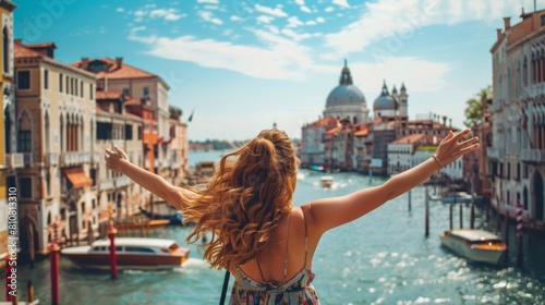 Ragazza che si diverte a braccia aperte in libertà, vista da dietro, durante una vacanza con sullo sfondo la città di Venezia, Italia