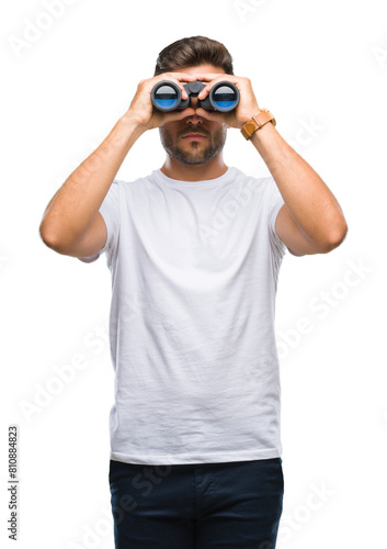 Young handsome man looking through binoculars over isolated background with a confident expression on smart face thinking serious