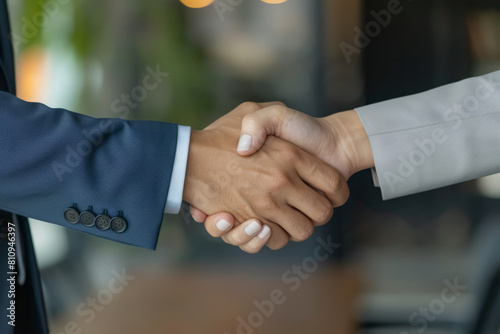 Dressed impeccably in suits, the mature Latin businessman and businesswoman share a moment of triumph as they shake hands firmly, finalizing their partnership business contract agreement during the