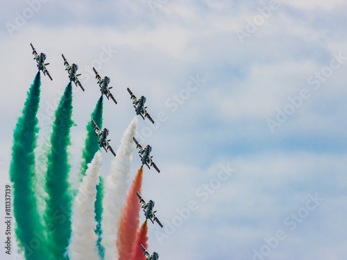 Air show, group of planes performing aerobatics, airplanes in flight in the blue sky, Italy.