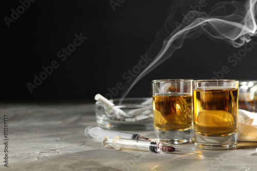 Alcohol and drug addiction. Whiskey in glasses and syringes on grey background, space for text