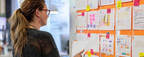 A product manager reviewing user story cards at a shared workspace, discussing design iterations