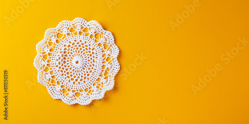 A white crochet doily on a yellow background.