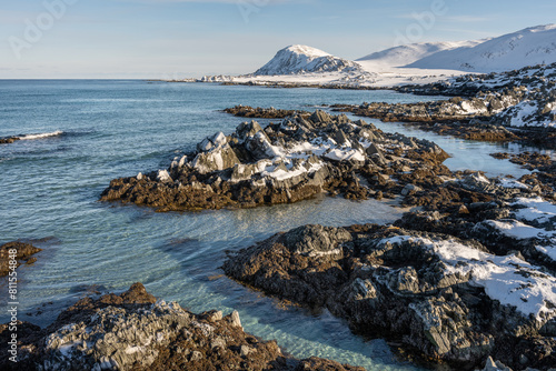 The rugged shores of Barents Sea and turquoise sea water on a cold and sunny winter day, Berlevåg, Varanger Peninsula, Norway