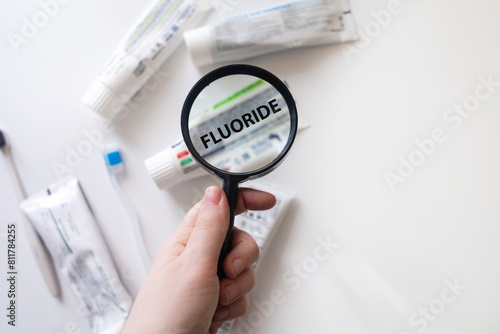 Dangerous toothpaste ingredient fluoride. Checking the composition of toothpaste with a magnifying glass against the background of many tubes