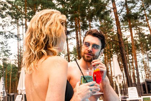 Cute guy sipping a glass of cocktail in his girlfriend company in the recreation area. Rest and relaxation concept