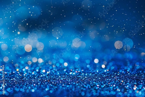A shiny blue background studded with particles shimmering in the light. Bright particles create a shimmering effect that resembles a starry sky or a magical glow. This backdrop is perfect for festive 