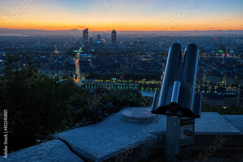 View of the city of Lyon France in the morning at dawn before sunrise from above. In the foreground there is a stone parapet and a spotting scope. Scenery. Background.