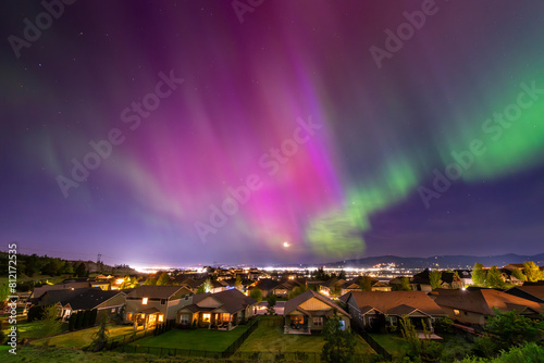 Late night view of the Aurora Borealis Northern Lights seen from a hillside subdivision in Liberty Lake overlooking the skyline and cities of Spokane and Spokane Valley, Washington State, USA.