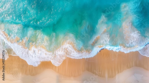 Top down drone shot of a beach with stunning blue water waves, creating a picturesque background for summer holiday themes