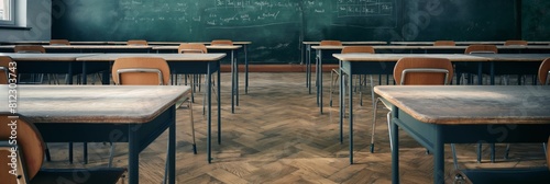 An image showcasing an empty classroom with rows of wooden desks facing a chalkboard written on with chalk