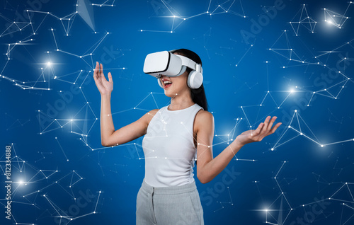Female standing wear white VR headset and white suit connect metaverse, future technology create cyberspace community. She looking around and gesticulate enjoy communicate other users. Hallucination.
