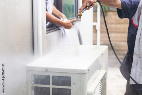 Air conditioner compressor with blurred technician man team cleaning air conditioner in background, Repairman washing dirty compartments air conditioner