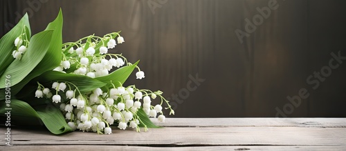 A bouquet of lily of the valley sits on a weathered wooden table creating a rustic aesthetic in the background with plenty of copy space for an image