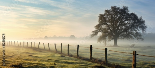 A misty morning scene with a wooden fence on a farm surrounded by fields offering a clear area for additional images or text