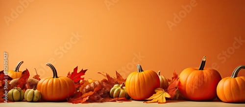 A fall scene with pumpkins and colorful leaves on an orange background providing copy space for images