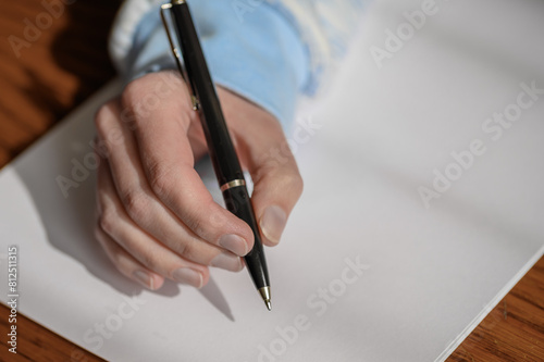 Długopis trzymany w ręce nad pusta biała kartka papieru, ręczne pisanie 
