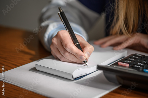 Kobieta siedzi przy stole w domu i liczy domowe finanse, rozpisuje budżet domowy