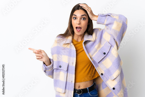 Young caucasian woman isolated on purple background surprised and pointing finger to the side
