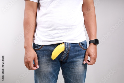 Limp drooping banana hanging from genital area of clothed unrecognizable man, impotence erectile dysfunction or limp-dick concept