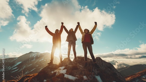 Three people raise their hands in the air, overcome obstacles together, and celebrate success and accomplishments at the top of a mountain.