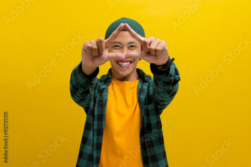Young Asian man, dressed in a casual shirt and wearing a beanie hat, is creating a triangle shape with his hands, symbolizing the concept of environmental protection, recycling, and reusing