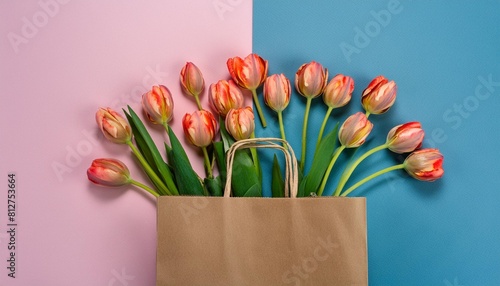 vibrant tulip flowers popping out of a brown paper shopping bag on pink and blue background