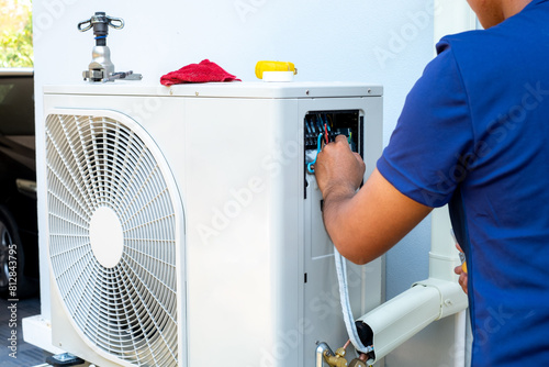 Male technician installing outdoor unit of air conditioner to cool the household in the summer. air compressor, electronic, hot summer, high temperature, Tropical countries